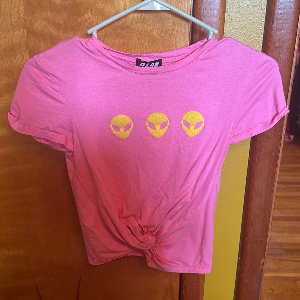 A bright pink crop top with lil yellow alien heads